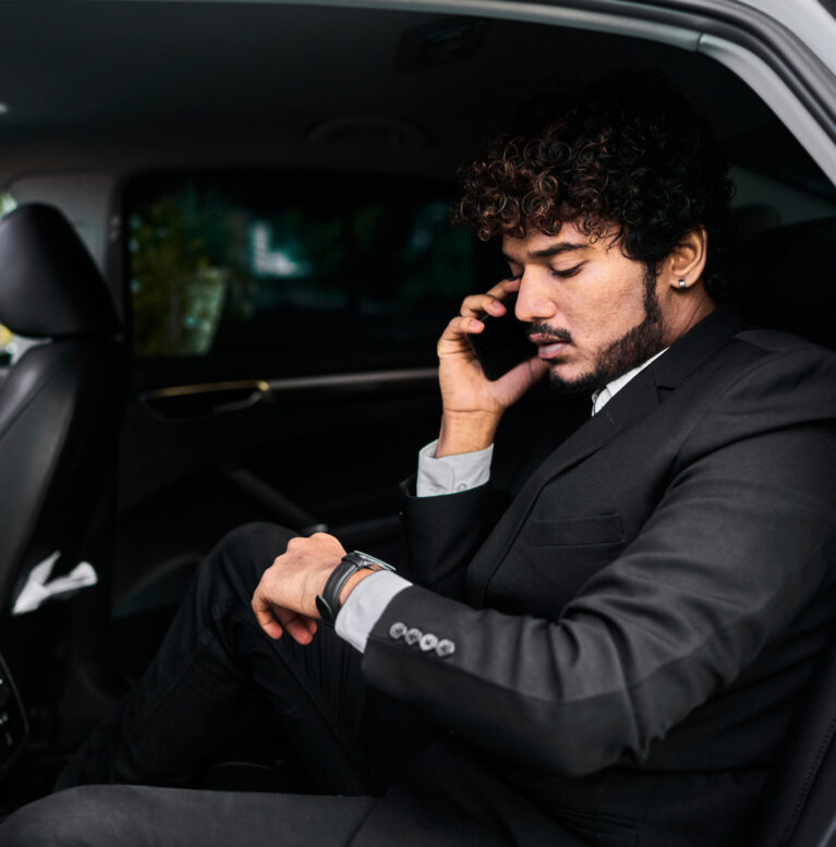 Curly-haired businessman in the backseat talking on the phone.